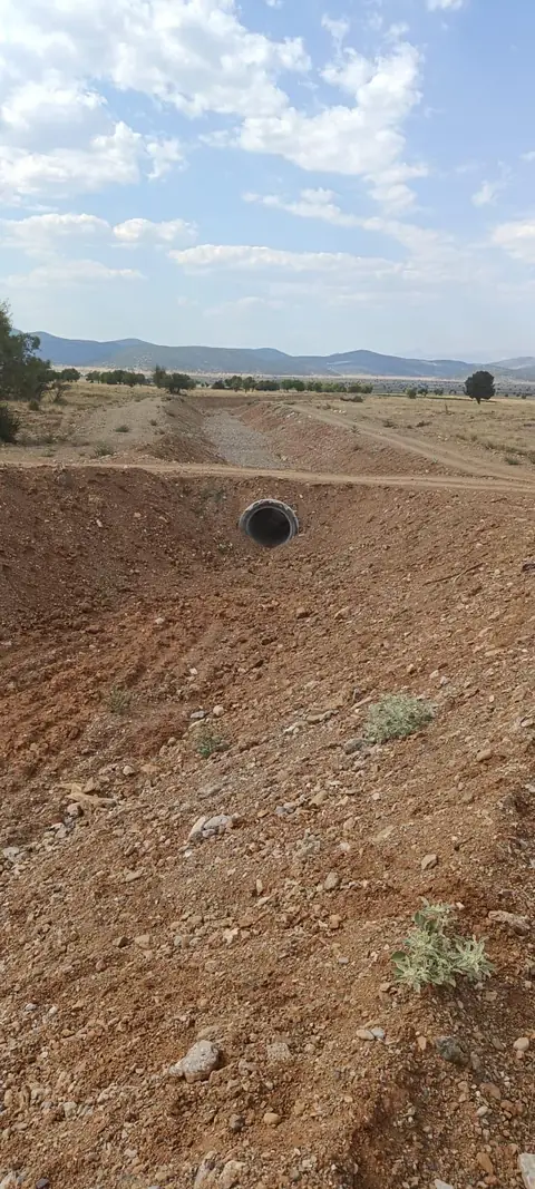 Yol geçişinin altındaki beton büz, arkada çakıllı kanal yatağı